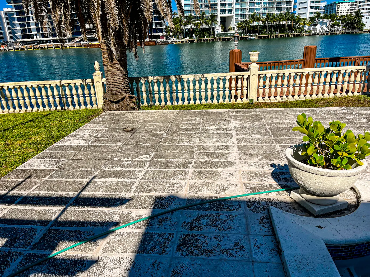 Waterfront terrace mid pressure washing — a sharp line between cleaned and dirty pavers